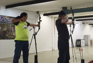 Two archers line up using tripods to assist in aiming their shots.
